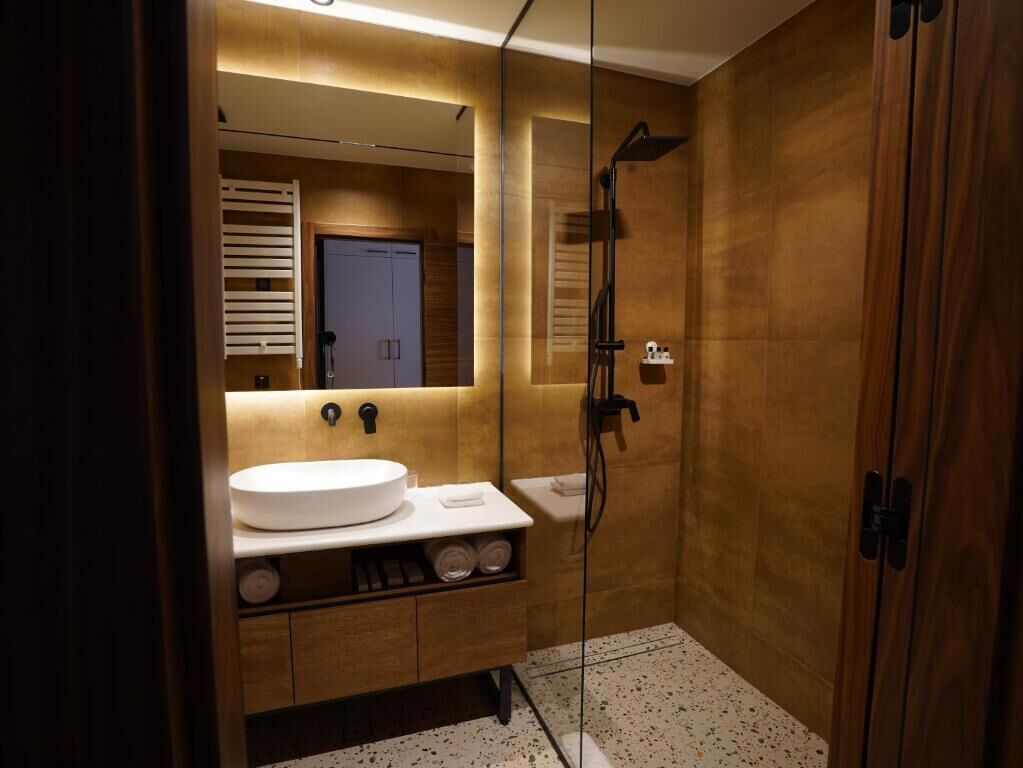 Un baño moderno con cabina de ducha de vidrio, un lavamanos con espejo y muebles de madera.