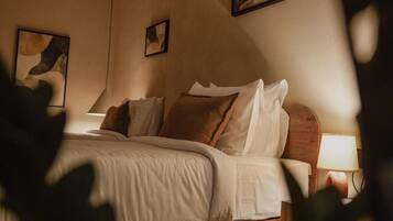 Une chambre à coucher avec un lit en bois, du linge de lit blanc et deux lampes fixées au mur.