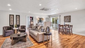 Un salon spacieux comprenant un canapé, deux fauteuils, une table basse et un coin repas avec une table et des chaises.