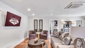 Un vaste espace de vie comprenant un canapé, deux fauteuils, une table basse et un élément décoratif mural.