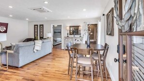 Un salon avec un canapé, une table à manger, des chaises et, au fond, une cuisine.
