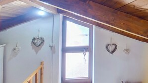 A room with a wooden ceiling, a window, and heart-shaped wall decorations. - Casa Sarda (Sennori)