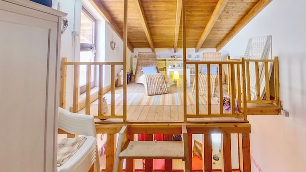 A wooden staircase leading to a loft bedroom with a bed, a chair, and a desk. - Casa Sarda (Sennori)