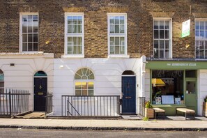 A building with a green sign reading 'The Sandwich Club,' a black door, and a small outdoor seating area. - 1 Min Walk to Euston Station, Modern Apartment (Greater London)
