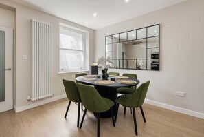 A dining area with a round table, green chairs, and a large mirror on the wall. - 10 Mins Walk to Bond Street, Marylebone Retreat (London)