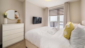 Ein Hotelzimmer mit Bett, Schminktisch, Fernseher und einem Fenster mit Vorhängen.