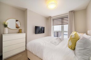 A hotel room with a bed, a dresser, a TV, and a window with curtains. - 10 Mins Walk to Bond Street, Marylebone Retreat (London)