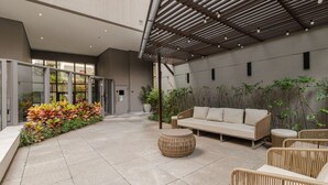 Ein moderner Außenbereich mit Sitzgelegenheiten, inklusive einer Couch und Korbstühlen, umgeben von Topfpflanzen und einer Pergola.