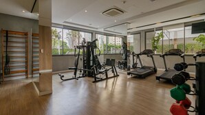 Ein Fitnessstudio mit Trainingsgeräten, großen Fenstern und Holzboden.