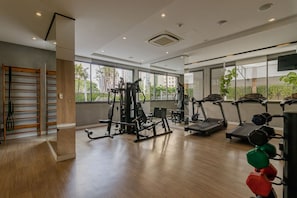 Ein Fitnessstudio mit Trainingsgeräten, großen Fenstern und Holzboden.