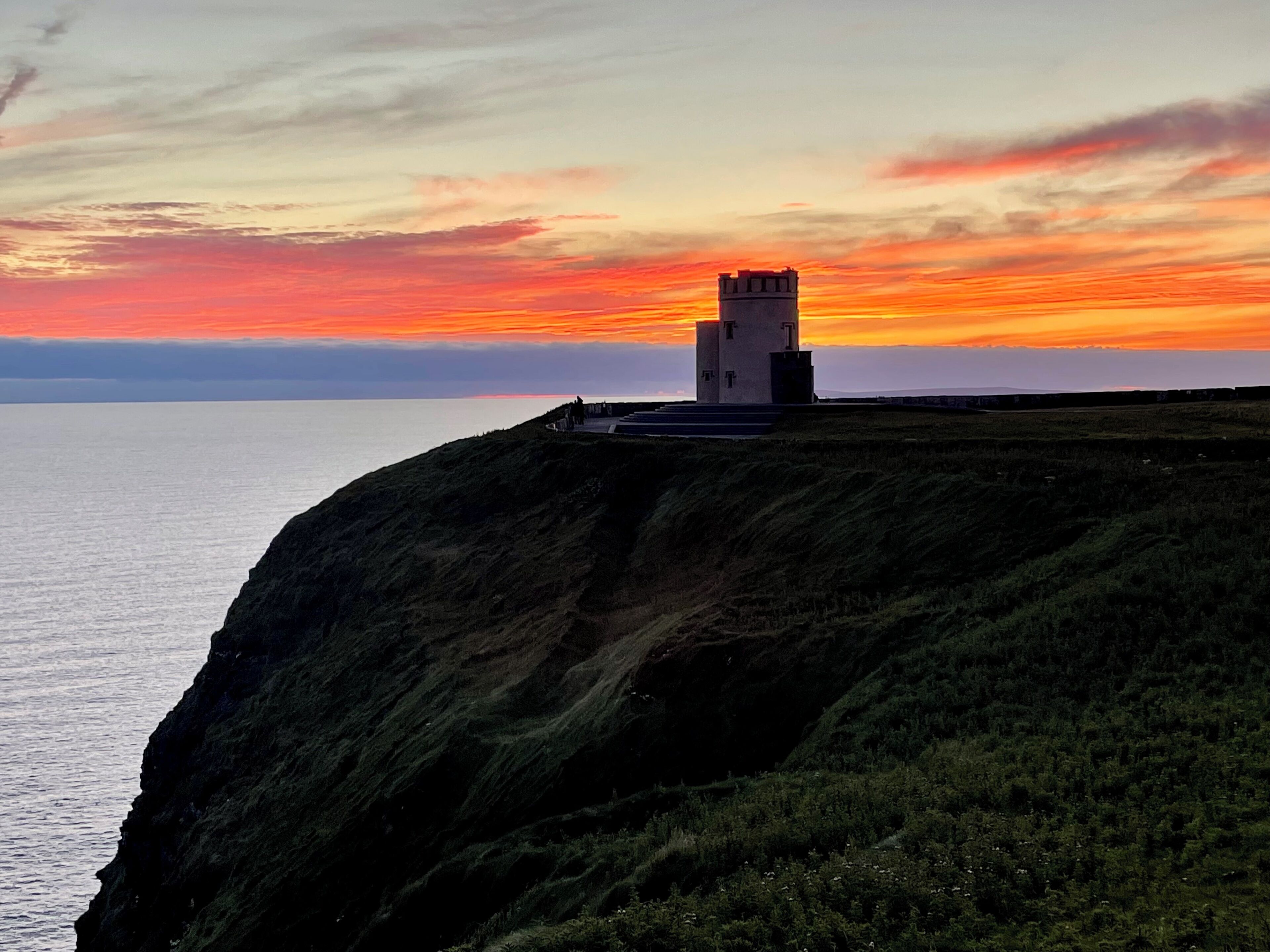 Un paysage côtier avec un phare perché sur une falaise surplombant la mer.