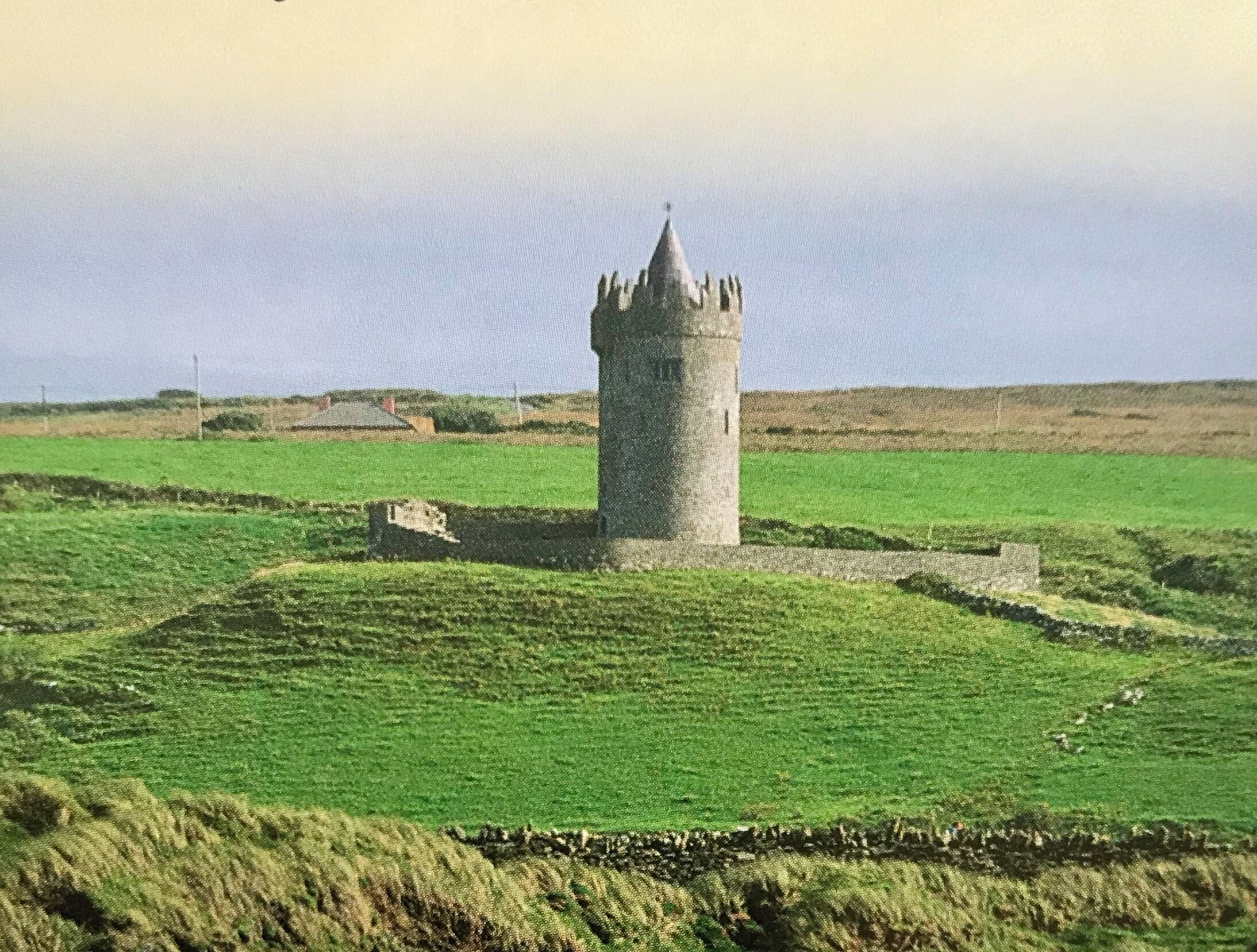 Uma estrutura de torre em um cenário rural, com campos abertos e céu claro.