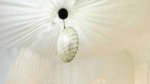Une chambre avec un grand lit, un luminaire suspendu, des tables de chevet avec des lampes et un radiateur.