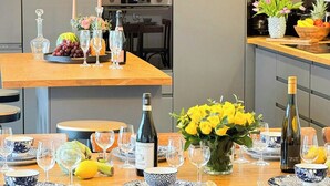 Un espace repas avec une table en bois dressée pour un repas, entourée de chaises.