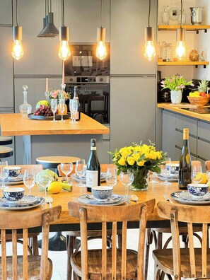 A dining area with a wooden table set for a meal, surrounded by chairs. - Breton house with footpath to coast in Finistère (Plouescat)
