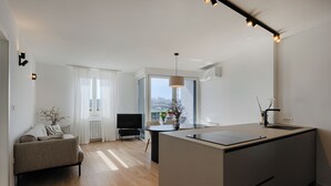 Eine moderne Wohnung mit Kücheninsel, Sofa, Fernseher und Blick auf die Stadt.