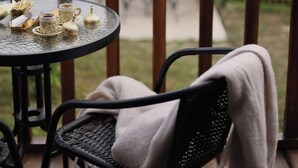 Un balcón con una mesa para dos, una silla y vistas a un paisaje montañoso.