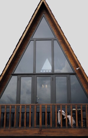 A triangular roof structure with large windows and a wooden railing.