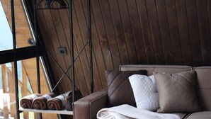 Una habitación acogedora con un sofá, un pequeño reposapiés y un escurridor de metal con toallas.