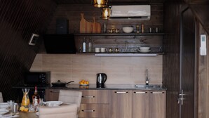 Cocina compacta con armarios de madera, microondas y comedor con mesa para dos.