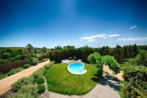 Ein Garten mit Pool, Rasen und Holzzaun.