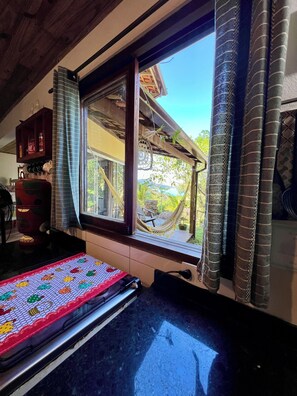 A kitchen with a large window, a hammock, and a colorful mat on the counter. - Exclusive chalet with sea and mountain views, just meters from the beach. (Paraty)
