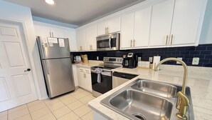 A modern kitchen with white cabinets, stainless steel appliances, and a marble countertop. -  1-bedroom condo in gorgeous Sea grove beach , pool and 5 min walk to the beach (Santa Rosa Beach)