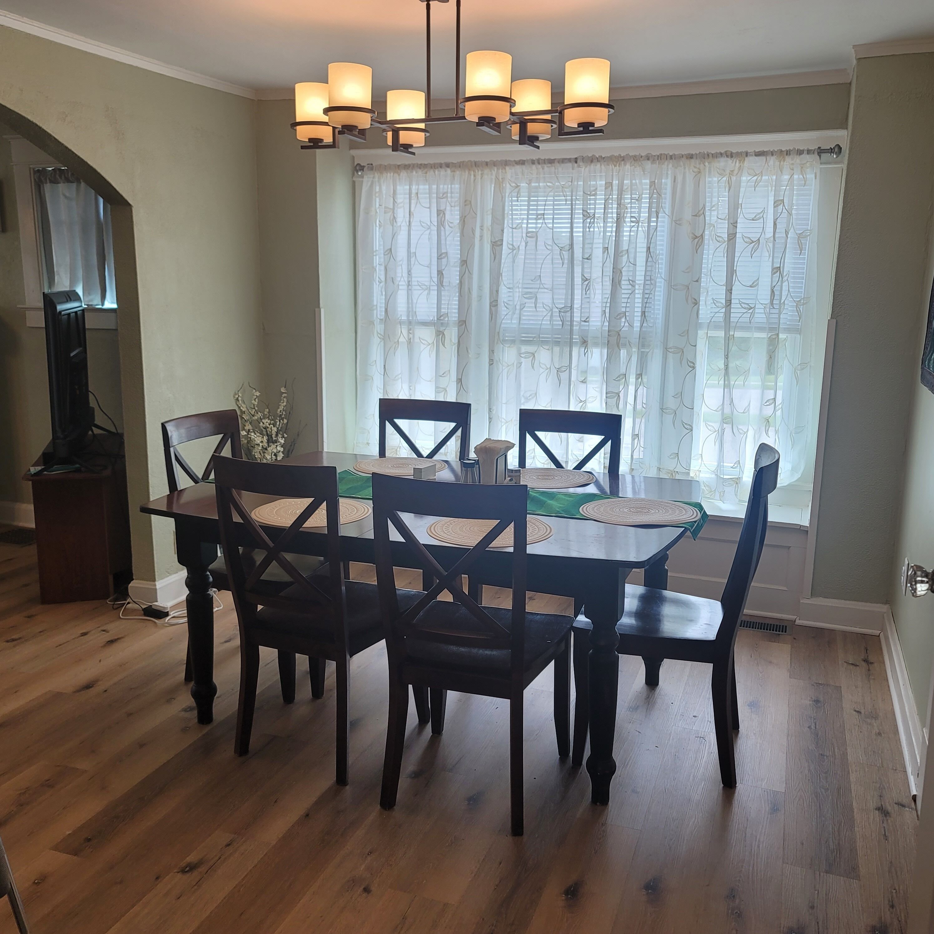 A dining area with a wooden table, chairs, and a chandelier.
