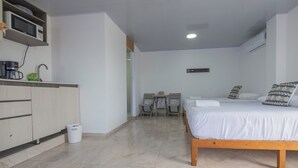 Una camera da letto con un letto, comodini, una scrivania e un angolo cottura.