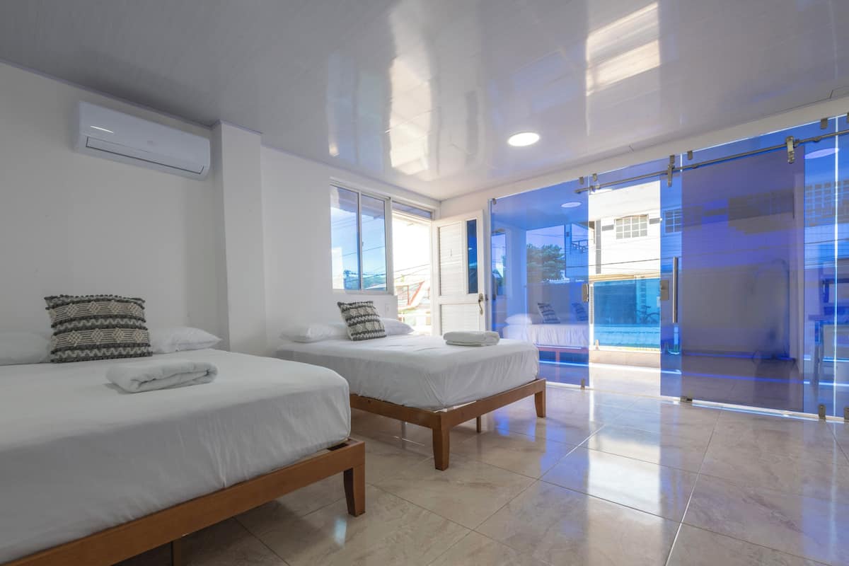 A hotel room with two beds, a window, and a view of the outside.