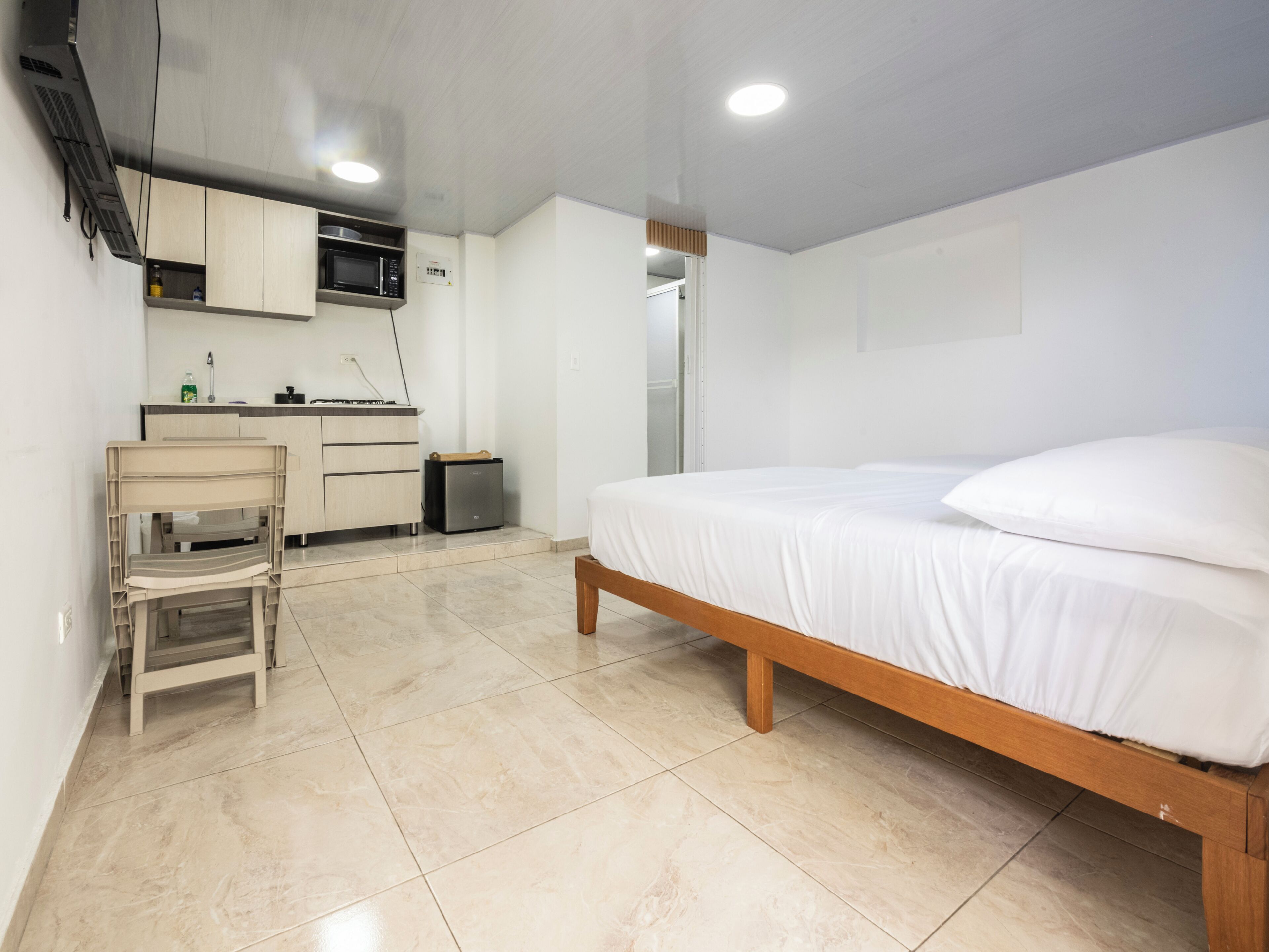 A bedroom with a bed, a small desk, a microwave, and a cabinet.