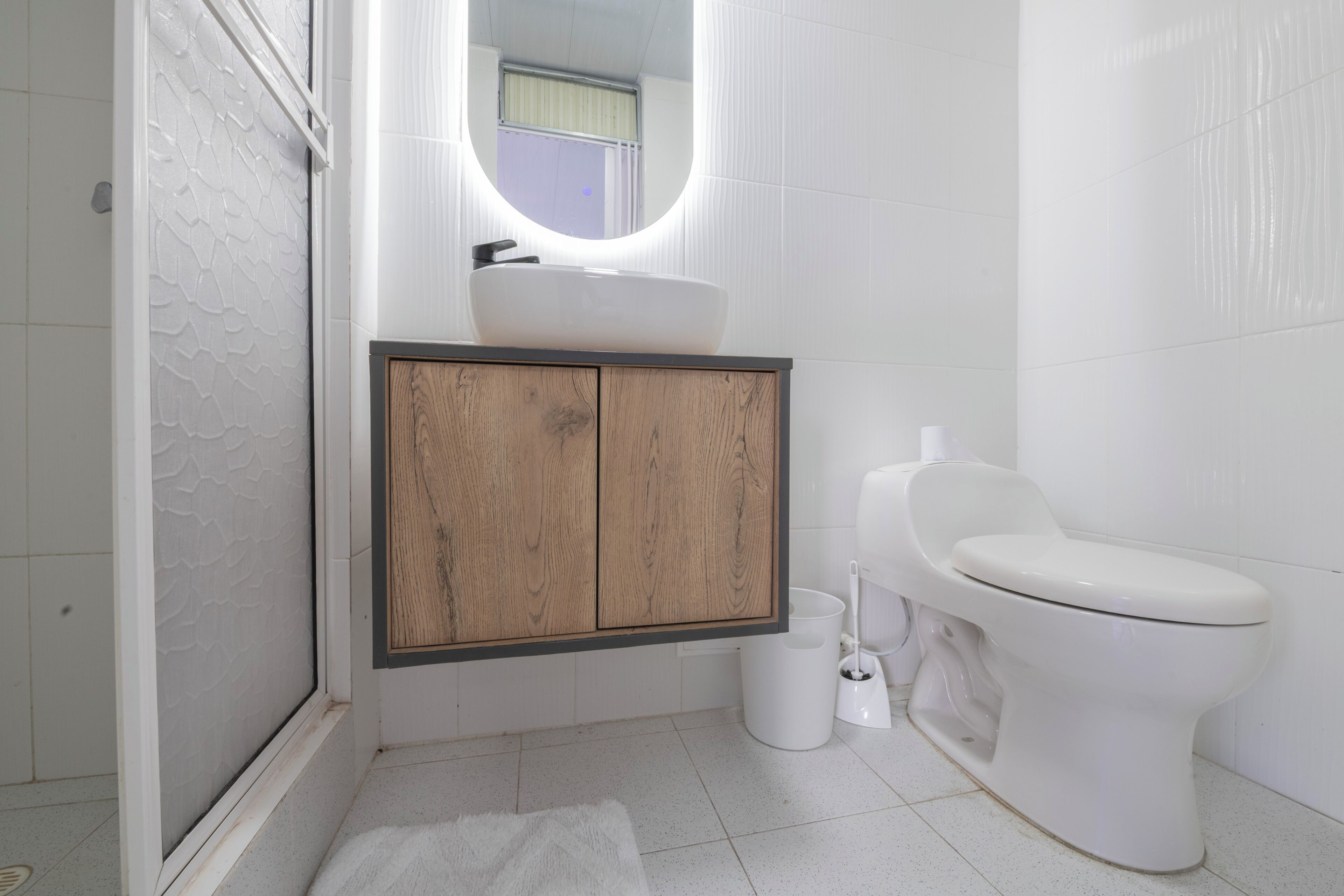 A bathroom with a white sink, wooden cabinet, toilet, and a mirror.