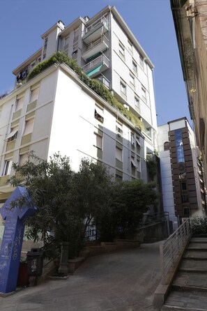 A multi-story building with balconies, a staircase, and a blue sign with text. - Very central, bright and multi-accessorised apartment ideal for families. (La Spezia)