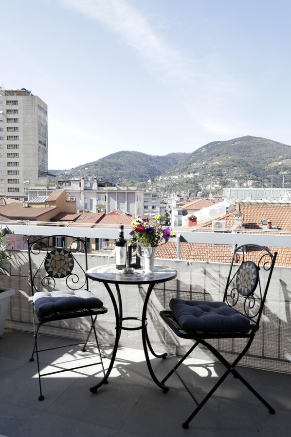A balcony with two chairs and a table, overlooking a cityscape with buildings and hills. - Very central, bright and multi-accessorised apartment ideal for families. (La Spezia)