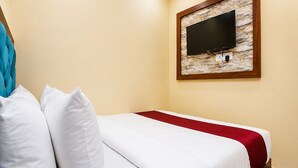 A hotel room with a bed, white pillows, a red bedspread, a television mounted on a stone wall, and a wooden frame. - Fabhotel Aai Om Residency (Mumbai)