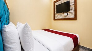 A hotel room with a bed, white pillows, a red blanket, a television mounted on a marble wall, and a wooden headboard. - Fabhotel Aai Om Residency (Mumbai)
