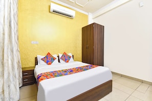 A hotel room with a bed, a wardrobe, an air conditioning unit, and a curtain. - Fabhotel Aqueens Plaza (Jaipur)