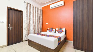 A bedroom with a bed, an air conditioner, a door, and a curtain.