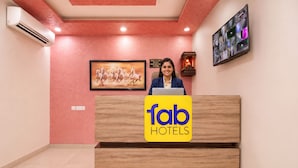 A reception desk with a logo for 'fab hotels,' a framed picture of horses, an air conditioning unit, and a wall-mounted display.