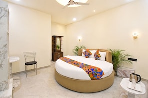 Une chambre à coucher moderne avec un lit rond, une table de chevet, une chaise, une commode et un ventilateur de plafond.