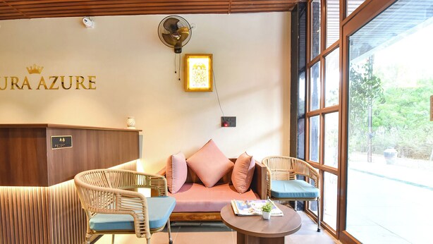 Un área de recepción con un sofá, dos sillones de mimbre, una mesita y un ventilador de pared.