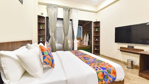 Una habitación de hotel con cama, televisor, armario y una planta pequeña.