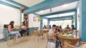 Un comedor con sillas y mesas de mimbre, una barra con un televisor y vistas al exterior.
