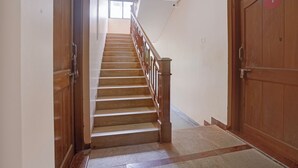 Una escalera de madera con barandilla, peldaños alfombrados y una puerta con número.