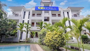 Un edificio de varios pisos con un letrero que dice 'fabHOTELS' y una piscina al frente.