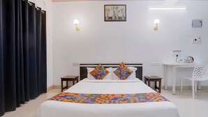 Une chambre d’hôtel comprenant un lit, deux tables de chevet, un bureau et une chaise.