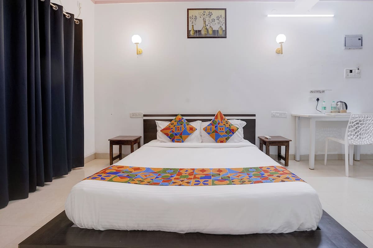 Habitación de hotel con cama, dos mesitas de noche, un escritorio y una silla.