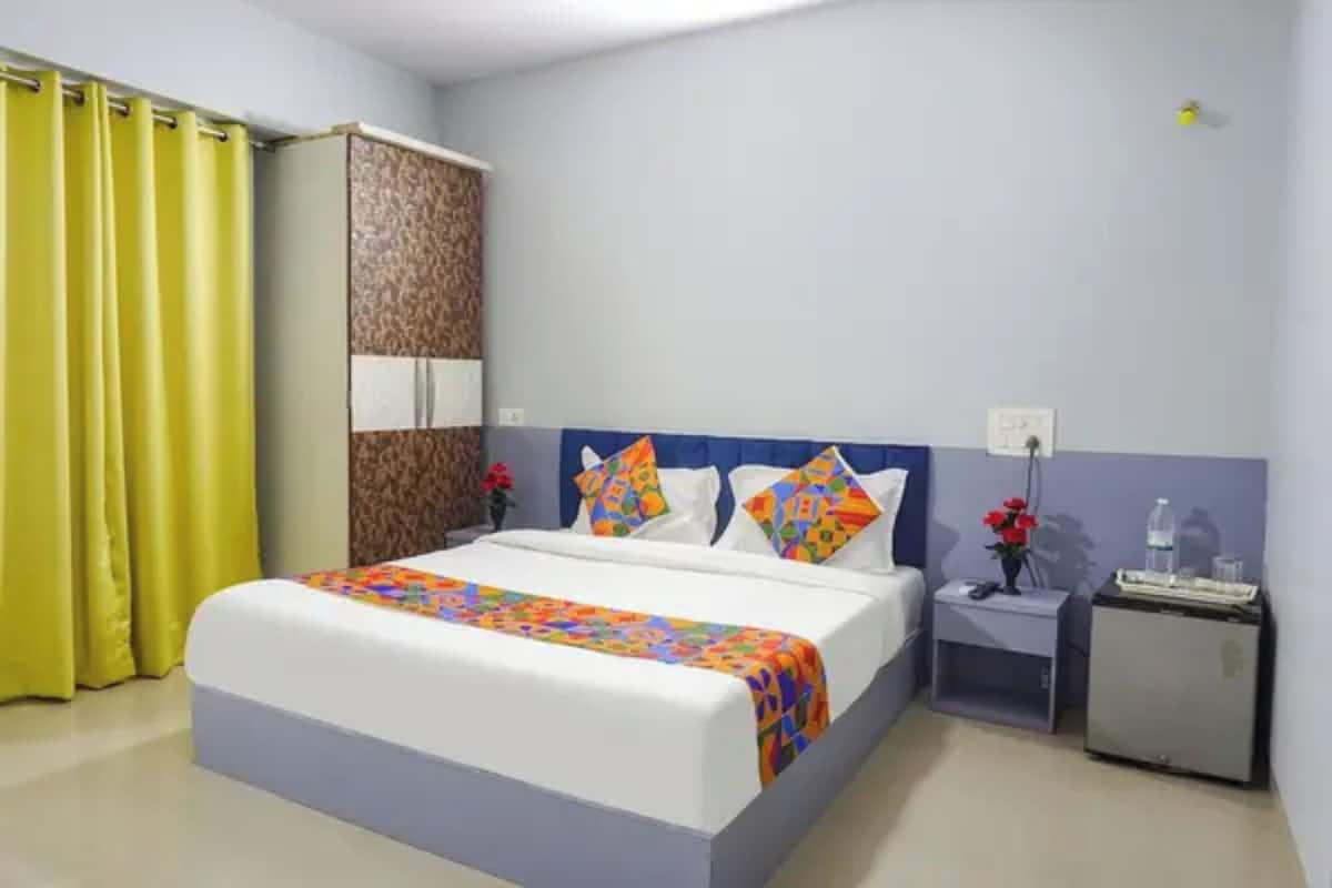 A hotel room with a bed, a wardrobe, a nightstand, and a desk.