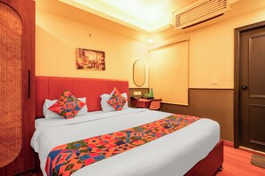 A hotel room with a bed, a desk, a chair, a mirror, and a door. - Fabhotel Bob'S (Patna)