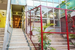 A staircase leading to a glass-walled area with a red metal structure. - Fabhotel Bob'S (Patna)